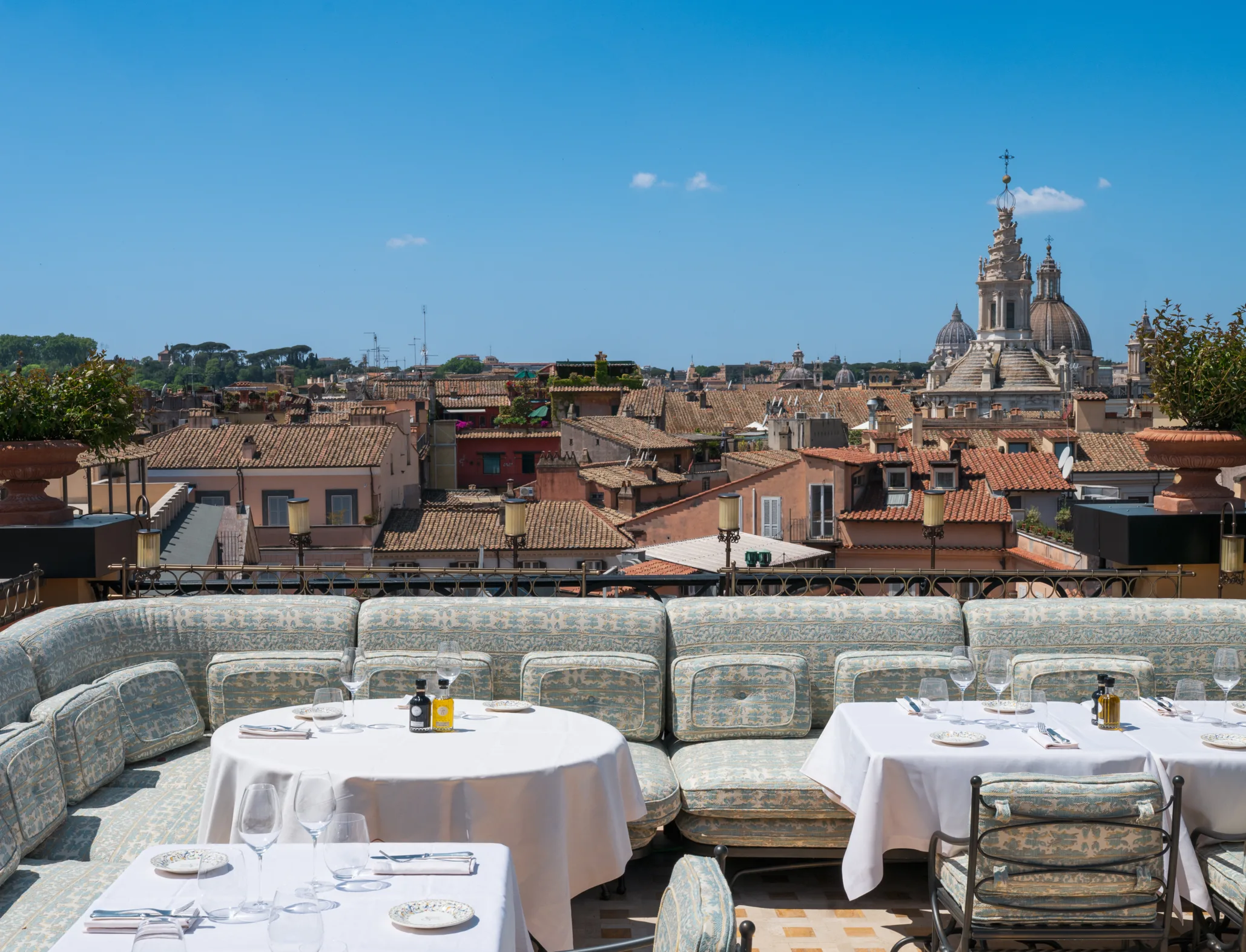 GIGI rooftop terrace showing set white-tablecloth dining tables overlooking Rome's terracotta roofs and church domes