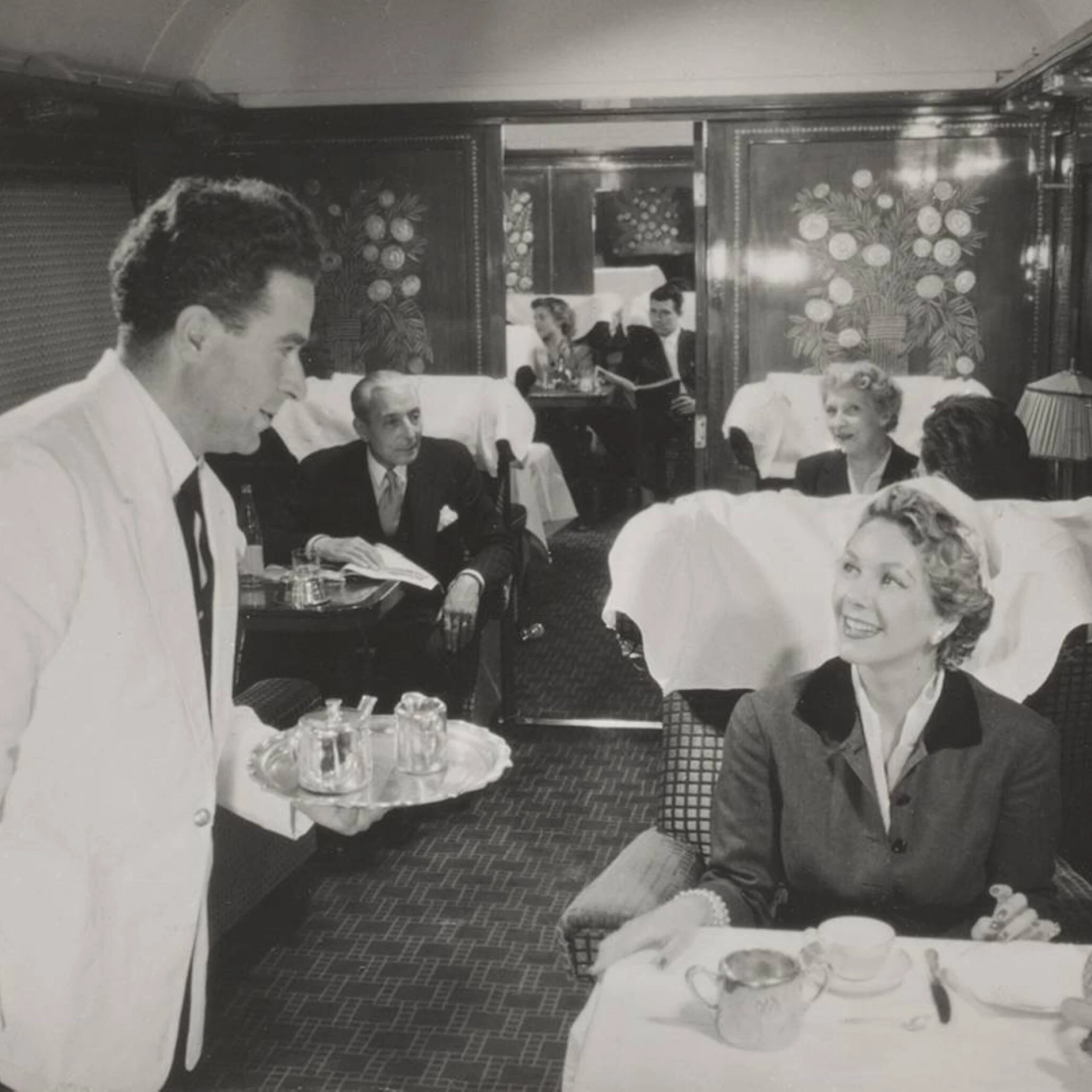 Orient Express serveur apportant le thé à une passagère souriante dans un wagon-salle à manger 1926 aux panneaux Lalique