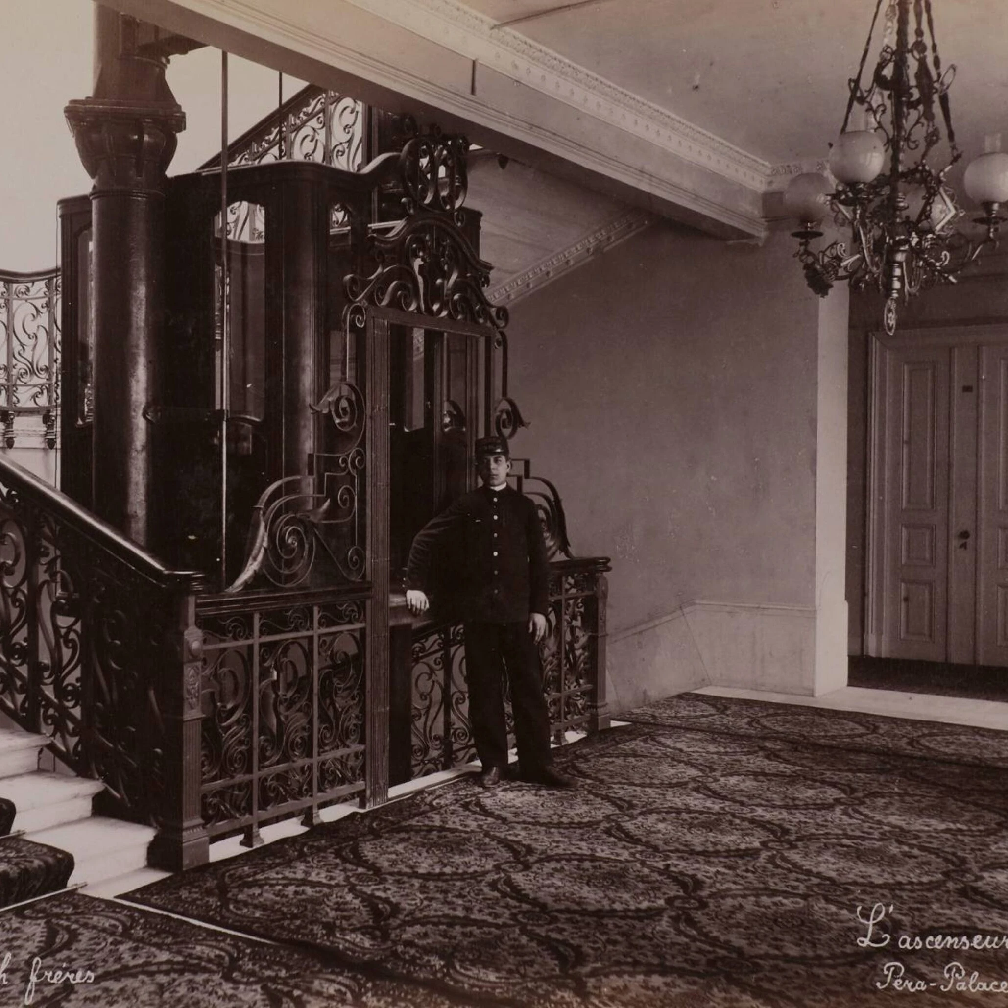 Ascenseur en fer forgé du Pera Palace avec portier en uniforme dans le hall historique de l'hôtel