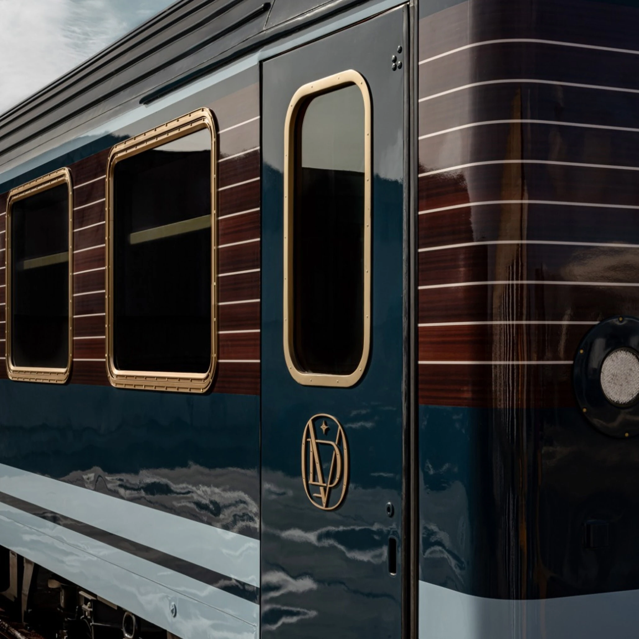  Voiture Le Grand Tour à carrosserie bleu nuit et fenêtres encadrées de laiton reflétant les nuages sur l'Orient-Express 